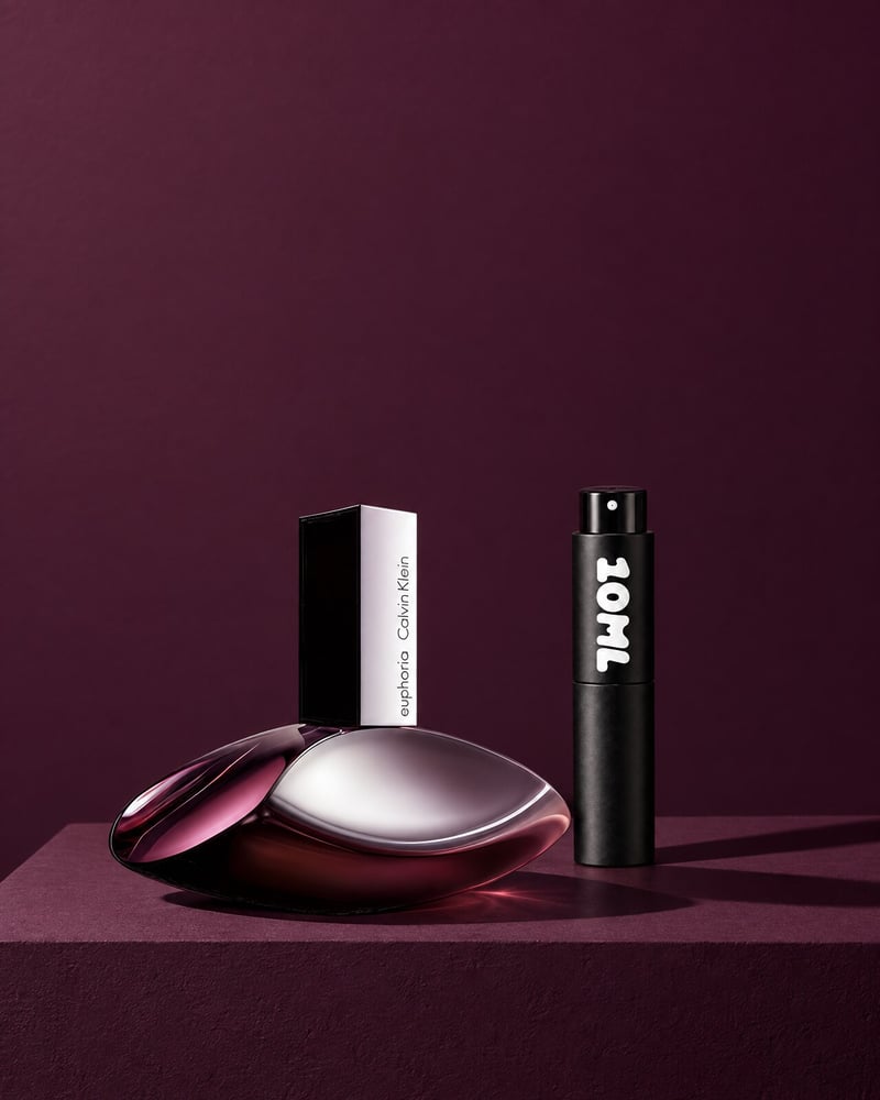 Calvin Klein Euphoria beside a 10ML travel atomiser on a purple plinth