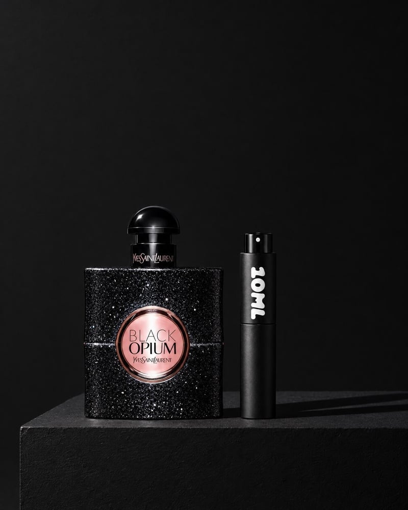 Yves Saint Laurent Black Opium beside a 10ML travel atomiser on a black plinth